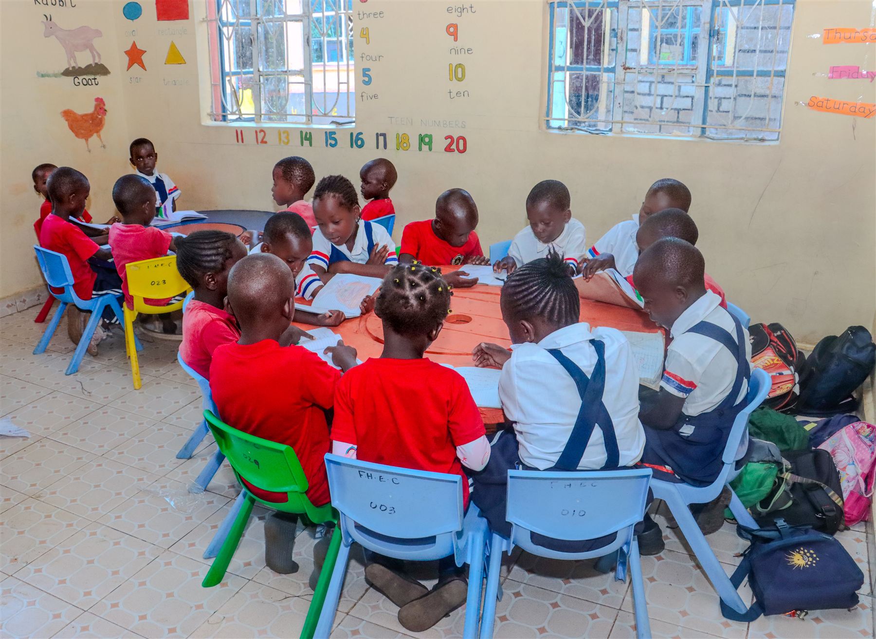 Learners reading together around a round table in a colourful classroom