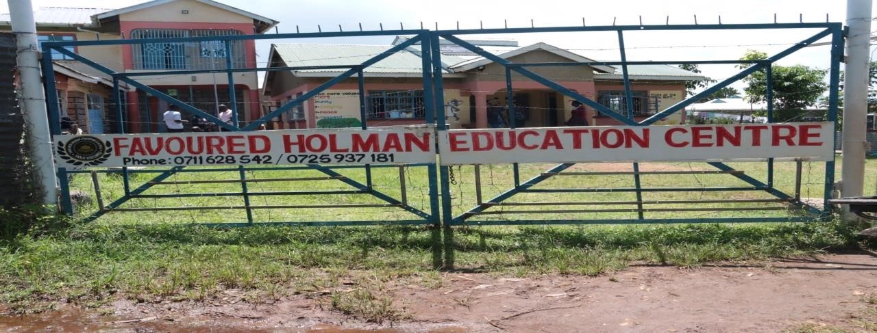 The gate of Favoured Holman Education Centre with the school buildings behind it